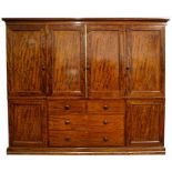 A 19th century figured mahogany triple wardrobe with central linen press with five slides above