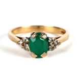 A 9ct gold ring set with a large central oval emerald flanked by white stones, approx UK size 'N'.