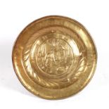 A large brass dish decorated in relief with religious figures, 42cms (16.5ins) diameter.