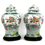 A pair of Chinese famille rose baluster vases and covers decorated with figures in a landscape, on