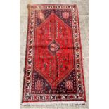 A Persian Shiraz woollen hand knotted rug with central gul decoration within a stylised floral