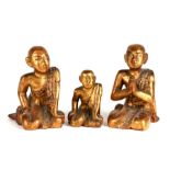 A group of three 19th century Burmese lacquer gilded and inlaid praying figures of priests, dated