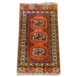 A Persian Bokhara rug with three central medallions on a burnt orange fround, 85 by 155cms (33.5