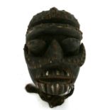 African / Tribal Art. An African wooden mask with deep caved protruding features, set all over