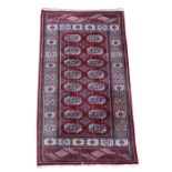 A Persian rug with sixteen central medallions on a red ground, 84 by 148cms (33 by 68ins).