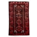 A hand knotted Turkoman rug with central medallions within a stylised foliate border on a red
