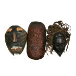 An armadillo shell face mask; together with a carved wooden mask and tribal wood carving (3).