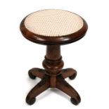 A Victorian walnut revolving piano stool on turned column and quatrefoil base.