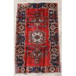 A Persian Baluch woollen hand knotted rug with stylised design on a beige ground, 239 by 178cms (