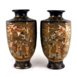 A pair of Japanese Satsuma vases decorated with figures within panels on a deep blue ground, red