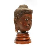 A large 19th century oriental carved and lacquered wood head of Buddha with headdress inlaid with