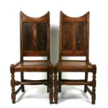 A pair of late 18th / early 19th century oak hall chairs, possibly Welsh, with panelled backs and