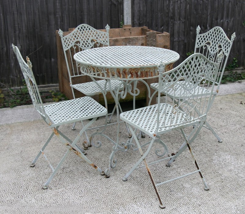 A green painted metal garden table and four matching chairs, the table 75cms (29.5ins) diameter.