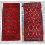 Two similar Persian Baluch woollen handmade rugs with geometric design on a red ground, each