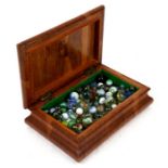 A quantity of vintage marbles in a mahogany box.