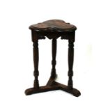 An oak occasional table with clover leaf shaped top, on three turned supports, 7cms (14.5ins)