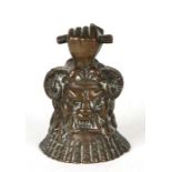 A bronze hand bell modelled as a mythical figure with clenched fist handle, 9cms (3.5ins) high.