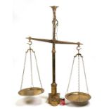 A large pair of floor standing brass balance scales and graduated weights with bull head terminal,