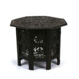 A Middle Eastern octagonal carved hardwood occasional table on a folding base, 46cms (18ins)