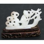 A Chinese jade carving depicting a figure in a boat, on a pierced hardwood stand, 8cms (3ins) long.