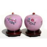 A pair of Chinese vases and covers of globular form, decorated with flowers on a pink sgraffito