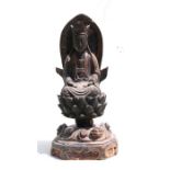 A Chinese carved and painted hardwood carving depicting a robed figure seated on a lotus flower,