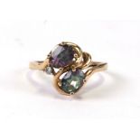 A 10ct gold cross-over ring set with two blue and purple stones and a small diamond, approx UK