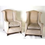 A pair of upholstered wing back armchairs on turned front supports.