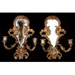 A pair of carved wood and gesso gilded twin-arm mirrored back wall sconces, 34cms (13.5ins) high.