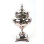 A continental silver plated jar and cover on stand with bow and foliate swag decoration, with cherub