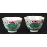 A pair of Chinese tea bowls decorated with ducks, lily pads and calligraphy, 6.5cms (2.5ins)