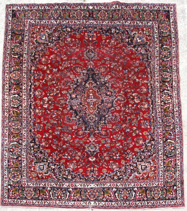 A Persian Meshed woollen hand knotted rug with foliate design on a red ground, 375 by 295cms (147.