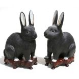 A pair of Chinese pottery rabbits on hardwood stands, 20cms (8ins) high.Condition ReportGlued repair