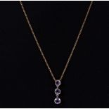 A 9ct gold necklace with three stone white gold mounted amethyst pendant.