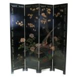 A Chinese lacquered four fold screen decorated with birds and bamboo on a black background,