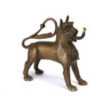 An Eastern bronze oil lamp in the form of a lion with spout and taper merging from its mouth,