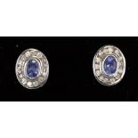 A pair of 9ct white gold stud earrings set with central oval tanzanite surrounded by diamonds.