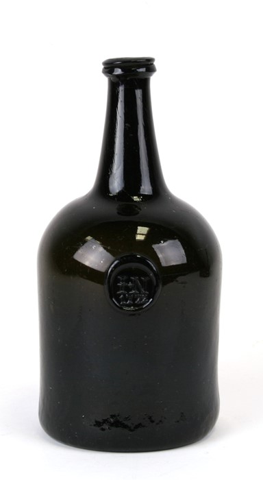 An 18th century dark amber glass seal bottle, initialled 'IN' and dated 1772, 23cms (9ins) high.