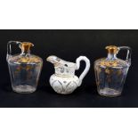 A pair of Victorian gilded glass jugs, 13cms (5ins) high; together with a white glass overlay