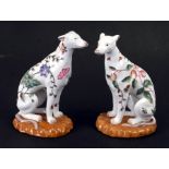 A pair of Chinese famille rose European style seated dog figures with red four character mark to the