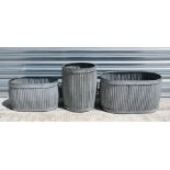 A group of three modern galvanised planters, the largest 64cms (25ins) wide.