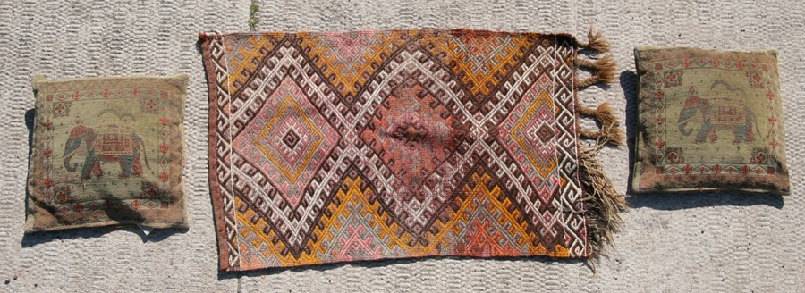 A Persian Soumak rug with three central medallions on a beige ground, 98 by 62cms; together with two