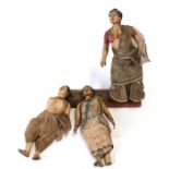 A group of three antique carved polychromed Indian wooden figures mounted on a wooden stand,