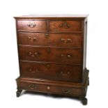 A Georgian oak chest of two short and three long graduated drawers, on a stepped base with a further