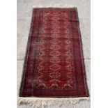 A Persian runner with a repeated geometric pattern on a red ground within a multi border, 83 by