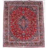 A Persian Meshed woollen hand knotted rug with foliate design on a red ground, 375 by 295cms (147.