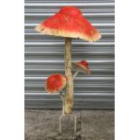 A decorative painted metal group of three toadstools.
