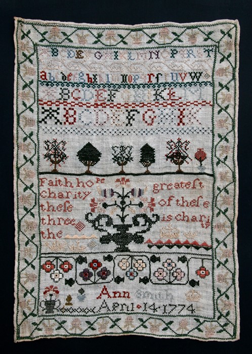 An 18th century needlework sampler decorated with alphabets and foliate arrangements with