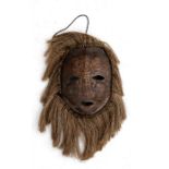 A Congo Lega tortoiseshell mask with fringe surround, 18cms (7ins) high without the fringe.