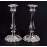 A pair of continental silver coloured metal candlesticks in the Rococo style, 24cms (9.5ins) high.